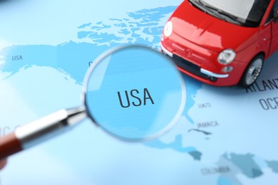 Photo of Looking at world map through magnifying glass and toy car, closeup