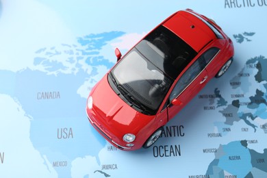 Photo of Road trip concept. Toy car on world map, above view