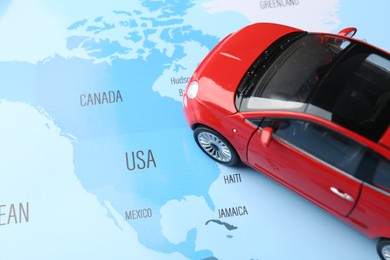 Photo of Road trip concept. Toy car on world map, above view