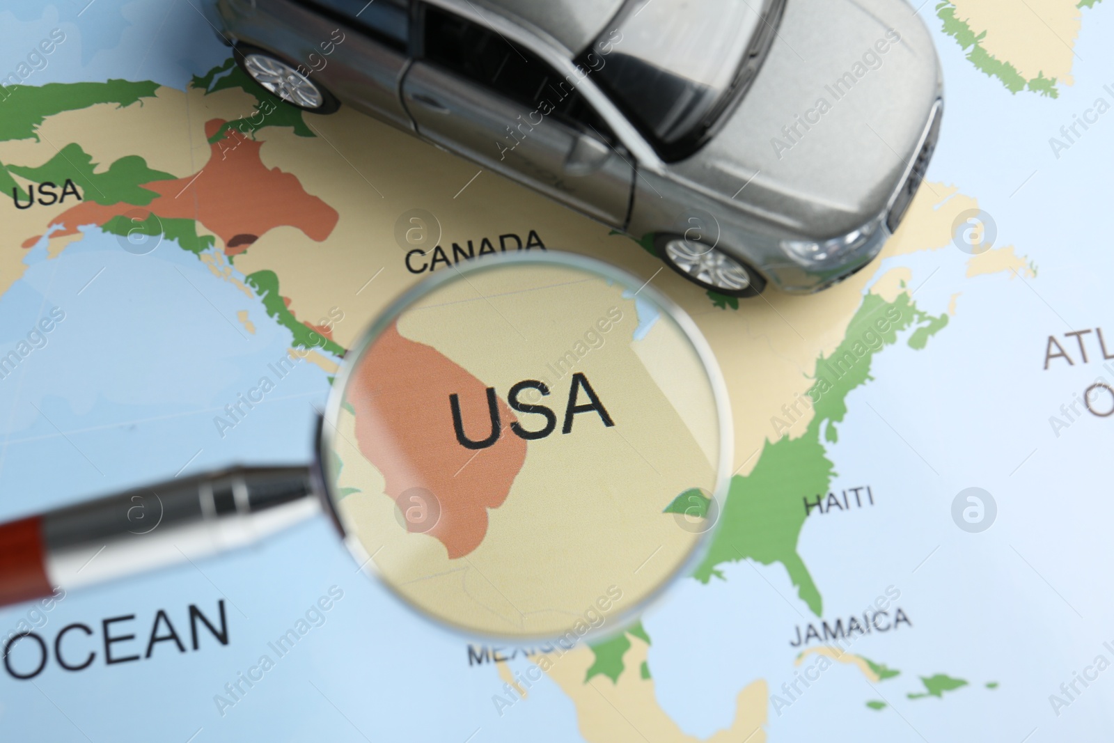 Road trip concept. Toy car and magnifying glass on world map, above view Photo of Road trip concept. Toy car and magnifying glass on world map, above view