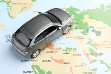 Photo of Road trip concept. Toy car on world map, above view