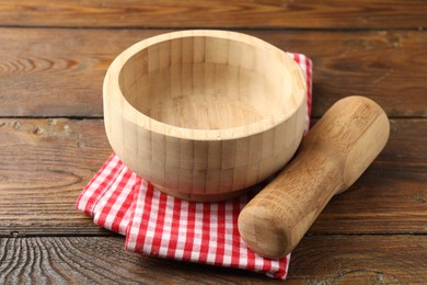 Photo of Mortar, pestle and cloth on wooden table, closeup