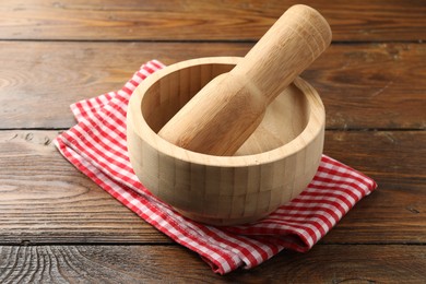 Photo of Mortar, pestle and cloth on wooden table, closeup