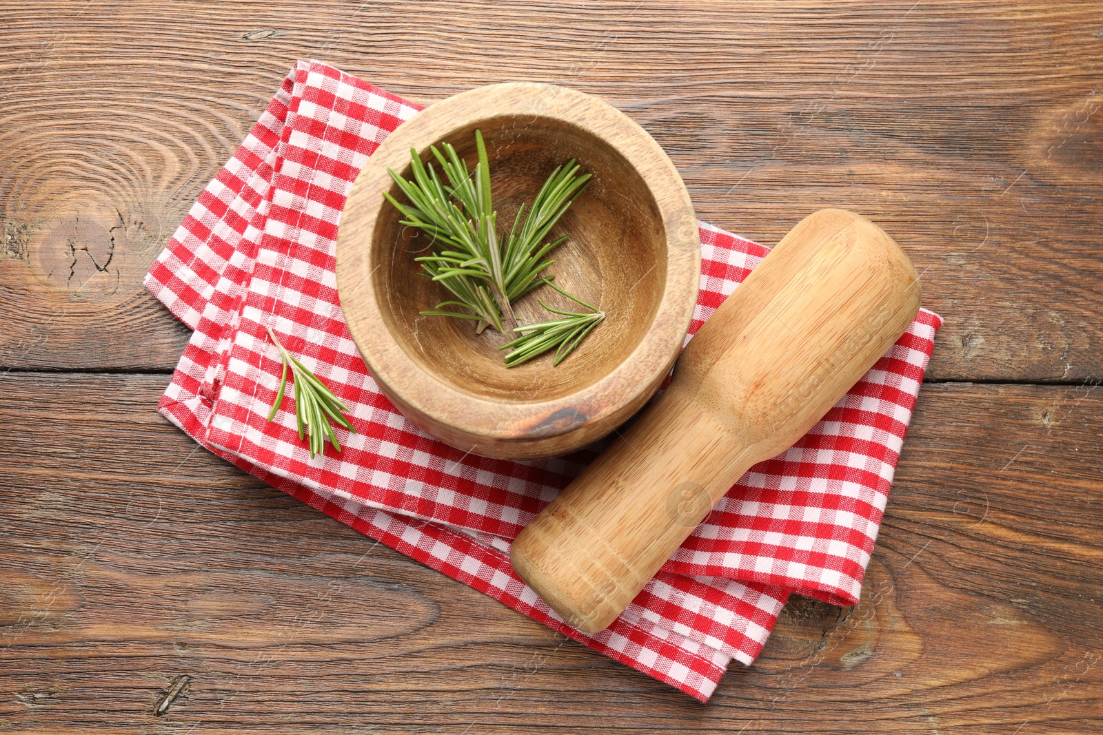 Mortar with rosemary, pestle and cloth on wooden table, flat lay Photo of Mortar with rosemary, pestle and cloth on wooden table, flat lay