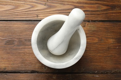 Photo of Marble mortar and pestle on wooden table, top view