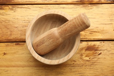 Photo of Mortar and pestle on wooden table, top view
