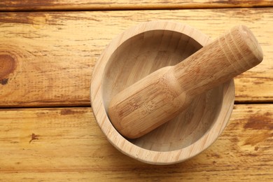Photo of Mortar and pestle on wooden table, top view