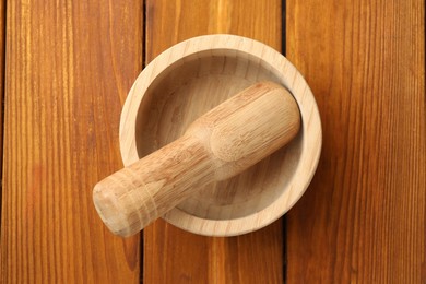 Photo of Mortar and pestle on wooden table, top view