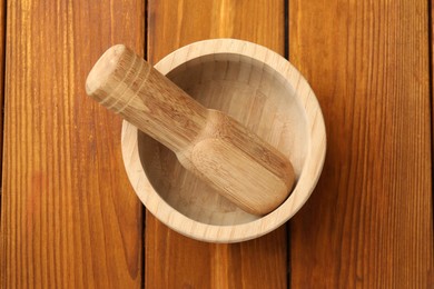 Photo of Mortar and pestle on wooden table, top view