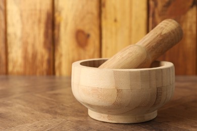 Photo of Mortar and pestle on wooden table, closeup. Space for text