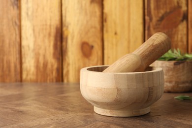 Photo of Mortar and pestle on wooden table, closeup. Space for text