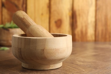 Photo of Mortar and pestle on wooden table, closeup. Space for text
