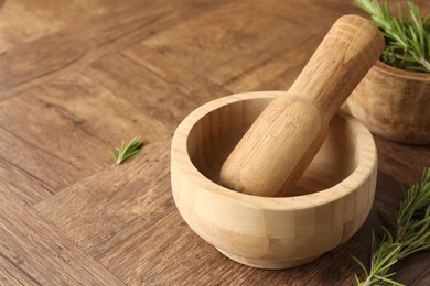 Photo of Mortar with rosemary and pestle on wooden table, closeup. Space for text