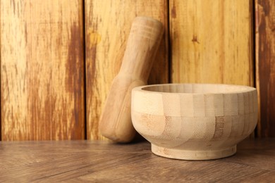 Photo of Mortar and pestle on wooden table, closeup. Space for text