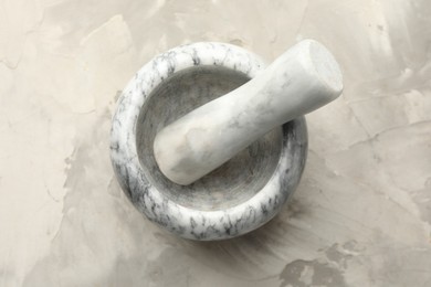 Photo of Marble mortar and pestle on grey textured table, top view