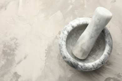 Photo of Marble mortar and pestle on grey textured table, top view. Space for text