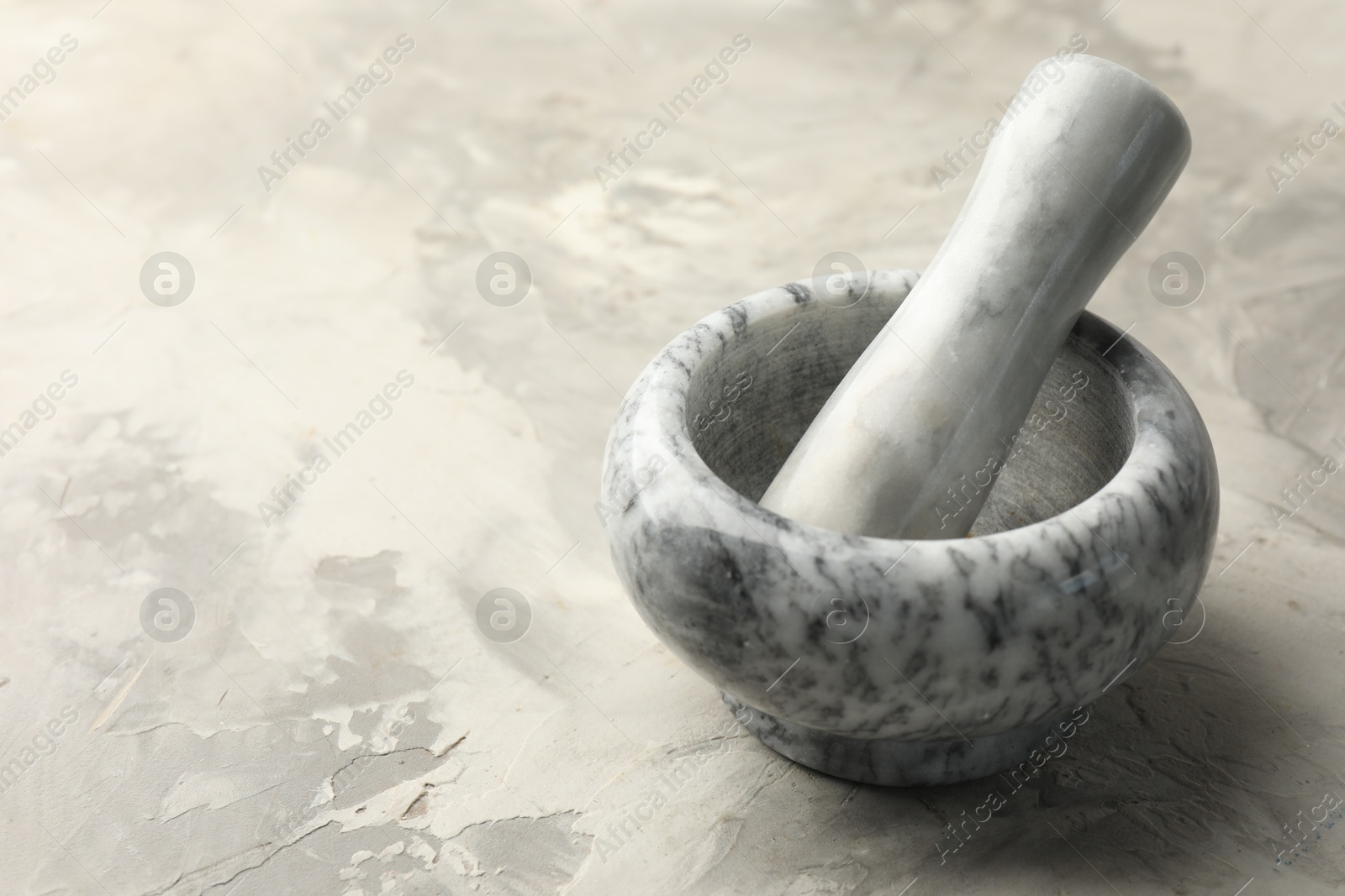 Marble mortar and pestle on grey textured table, closeup. Space for text Photo of Marble mortar and pestle on grey textured table, closeup. Space for text