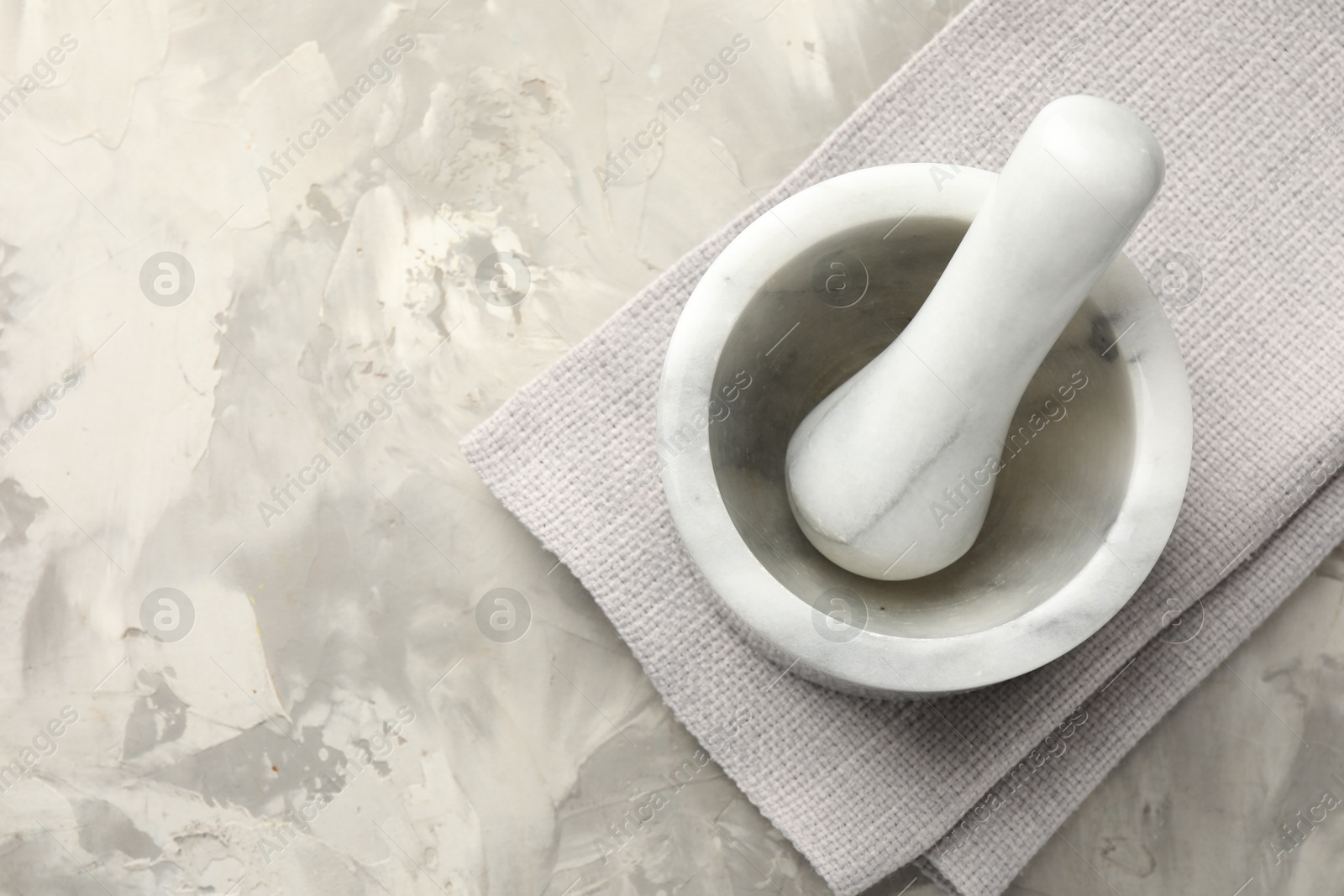 Marble mortar, pestle and cloth on grey textured table, top view. Space for text Photo of Marble mortar, pestle and cloth on grey textured table, top view. Space for text