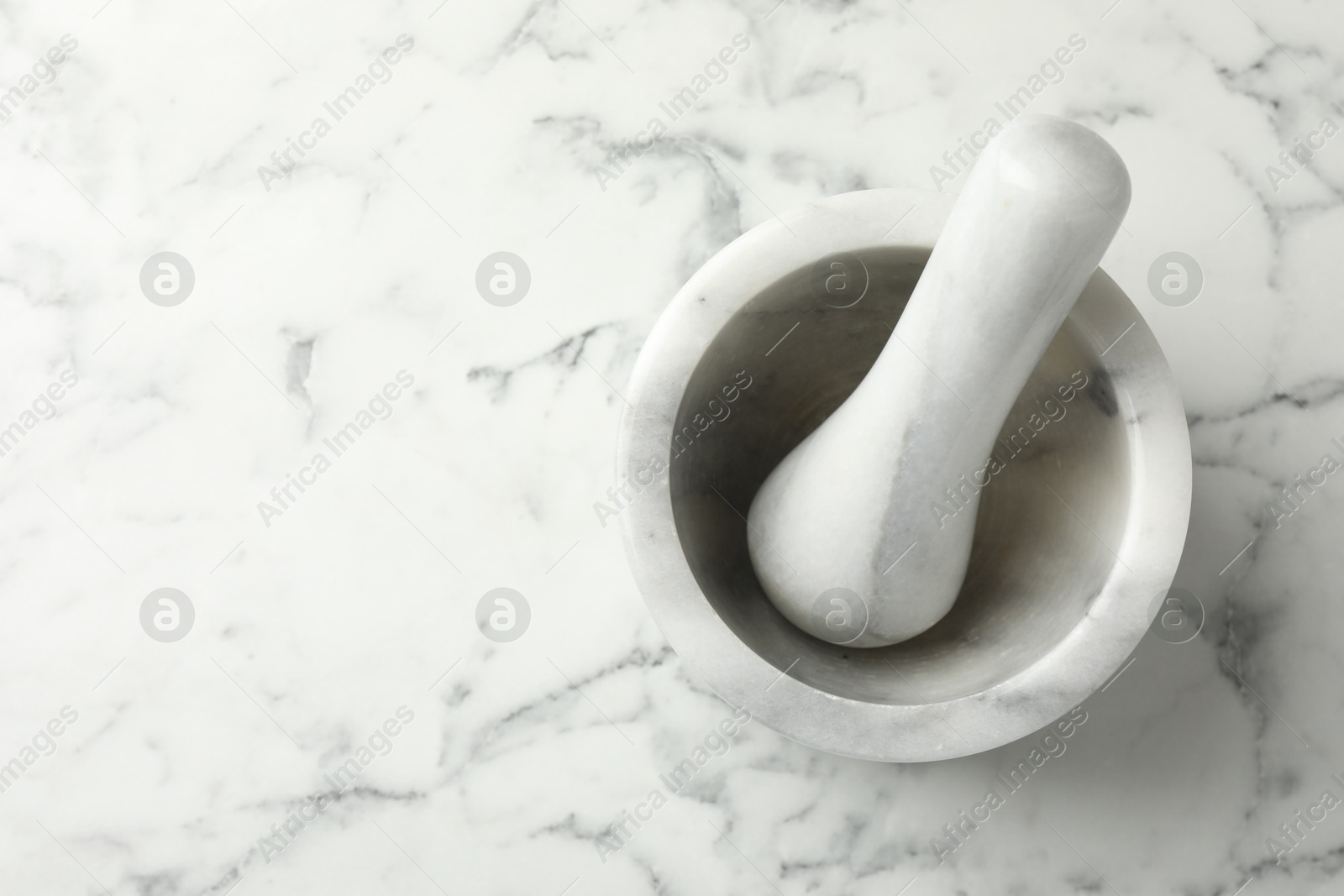 Mortar and pestle on white marble table, top view. Space for text Photo of Mortar and pestle on white marble table, top view. Space for text