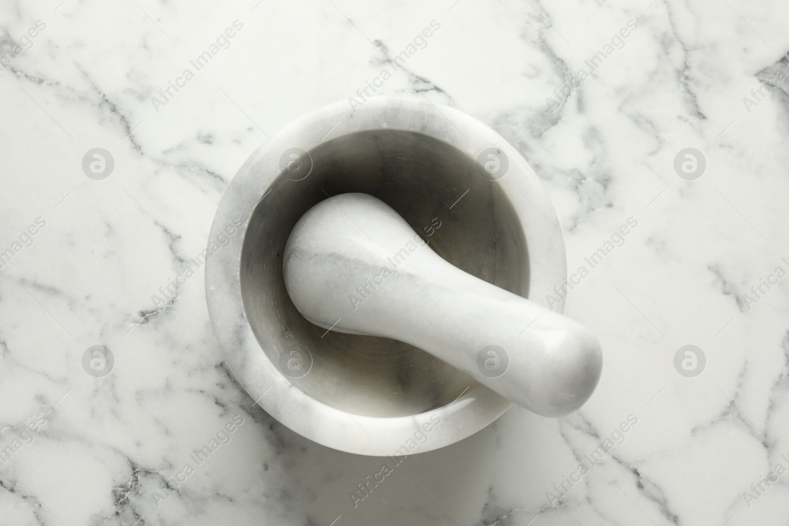 Mortar and pestle on white marble table, top view Photo of Mortar and pestle on white marble table, top view