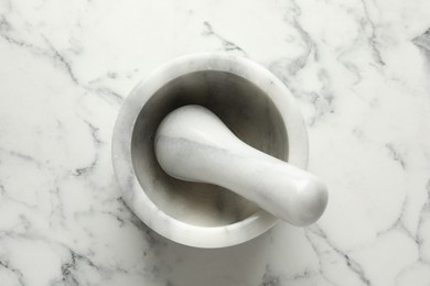 Photo of Mortar and pestle on white marble table, top view