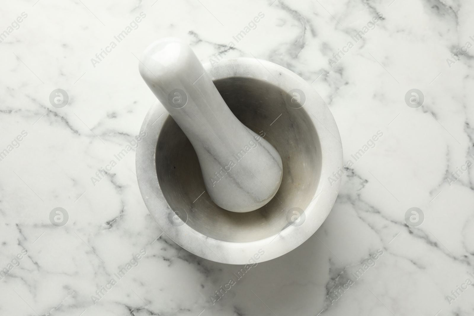 Mortar and pestle on white marble table, top view Photo of Mortar and pestle on white marble table, top view
