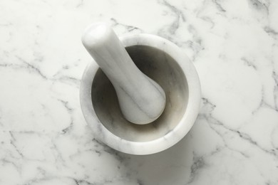 Photo of Mortar and pestle on white marble table, top view