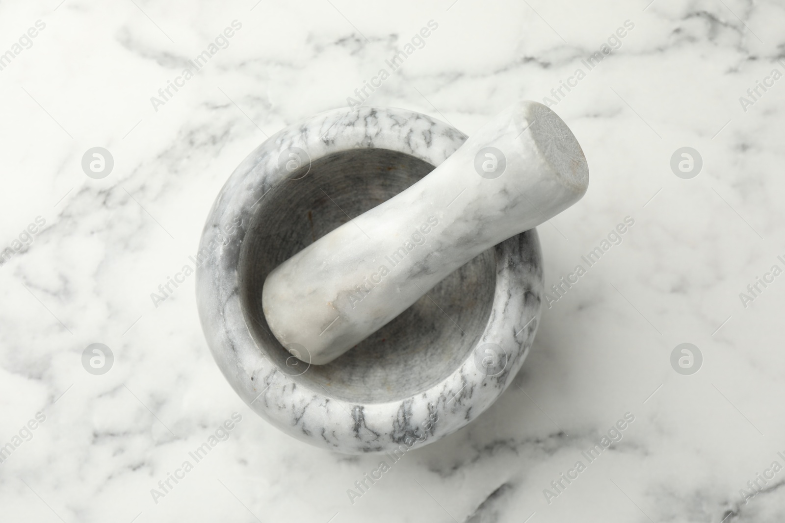 Mortar and pestle on white marble table, top view Photo of Mortar and pestle on white marble table, top view