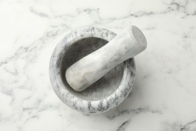 Photo of Mortar and pestle on white marble table, top view
