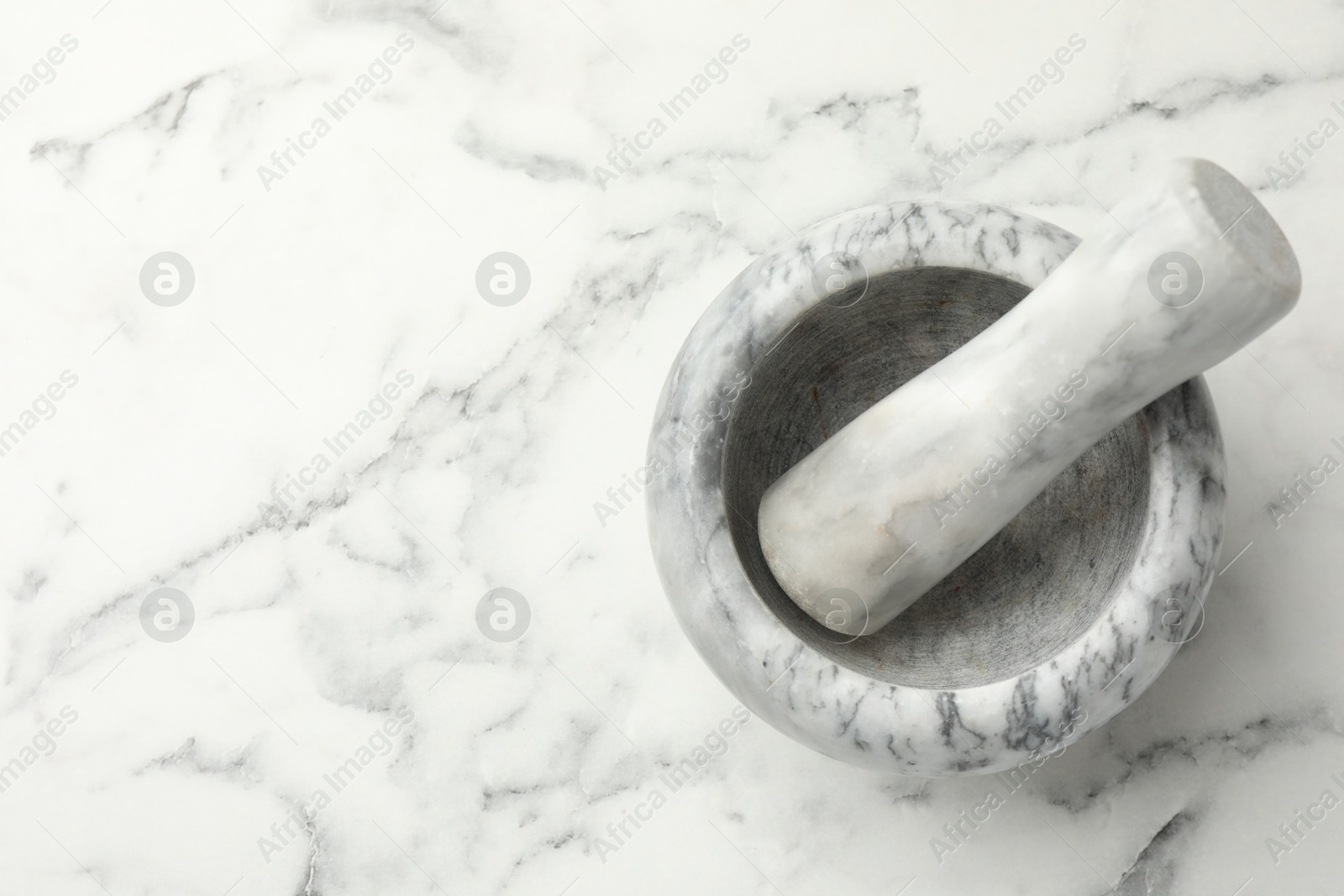 Mortar and pestle on white marble table, top view. Space for text Photo of Mortar and pestle on white marble table, top view. Space for text