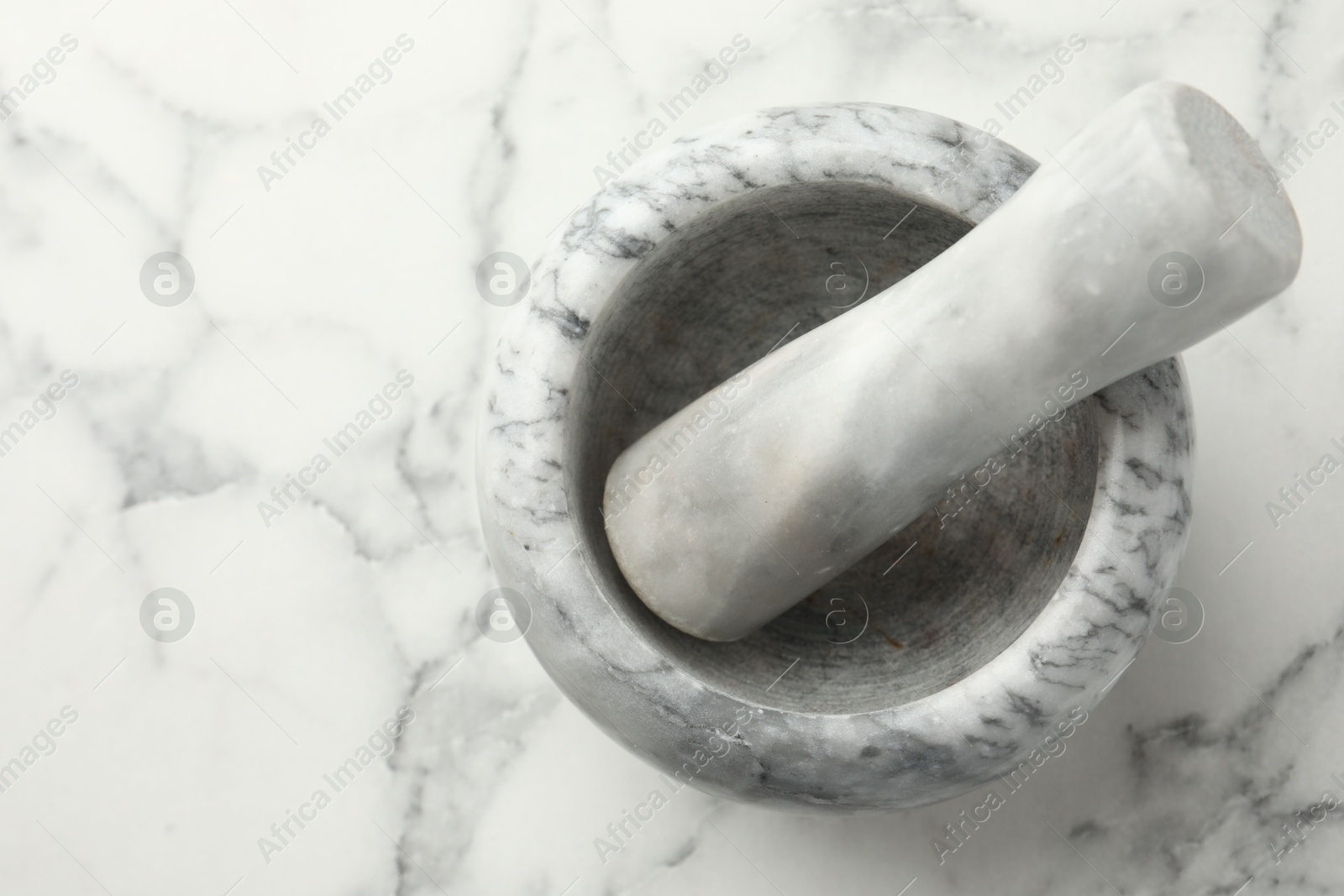 Mortar and pestle on white marble table, top view. Space for text Photo of Mortar and pestle on white marble table, top view. Space for text