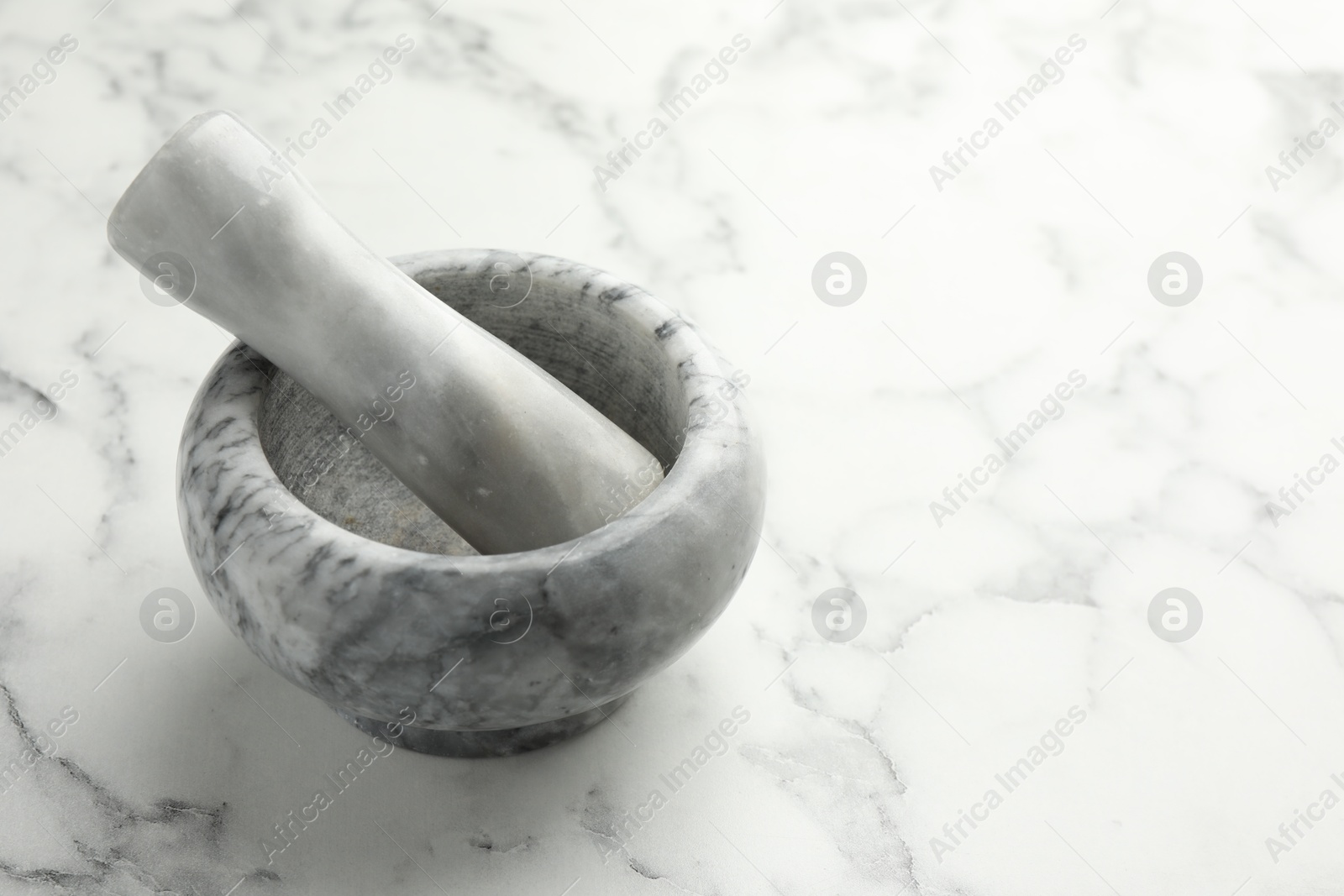 Mortar and pestle on white marble table, closeup. Space for text Photo of Mortar and pestle on white marble table, closeup. Space for text