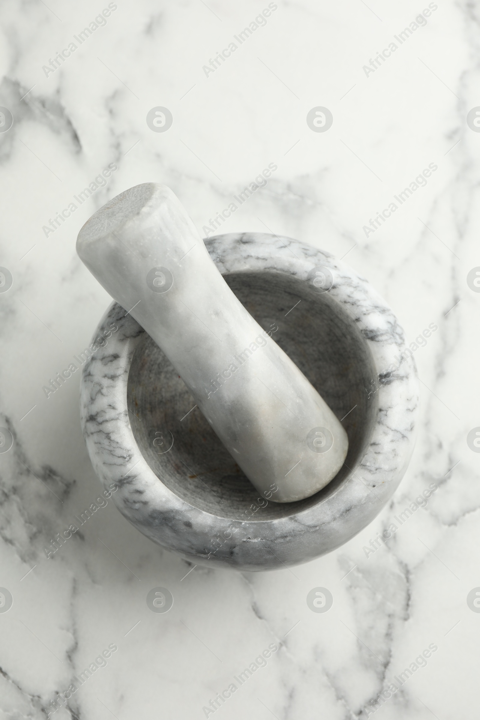 Mortar and pestle on white marble table, top view Photo of Mortar and pestle on white marble table, top view