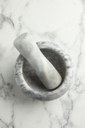 Photo of Mortar and pestle on white marble table, top view