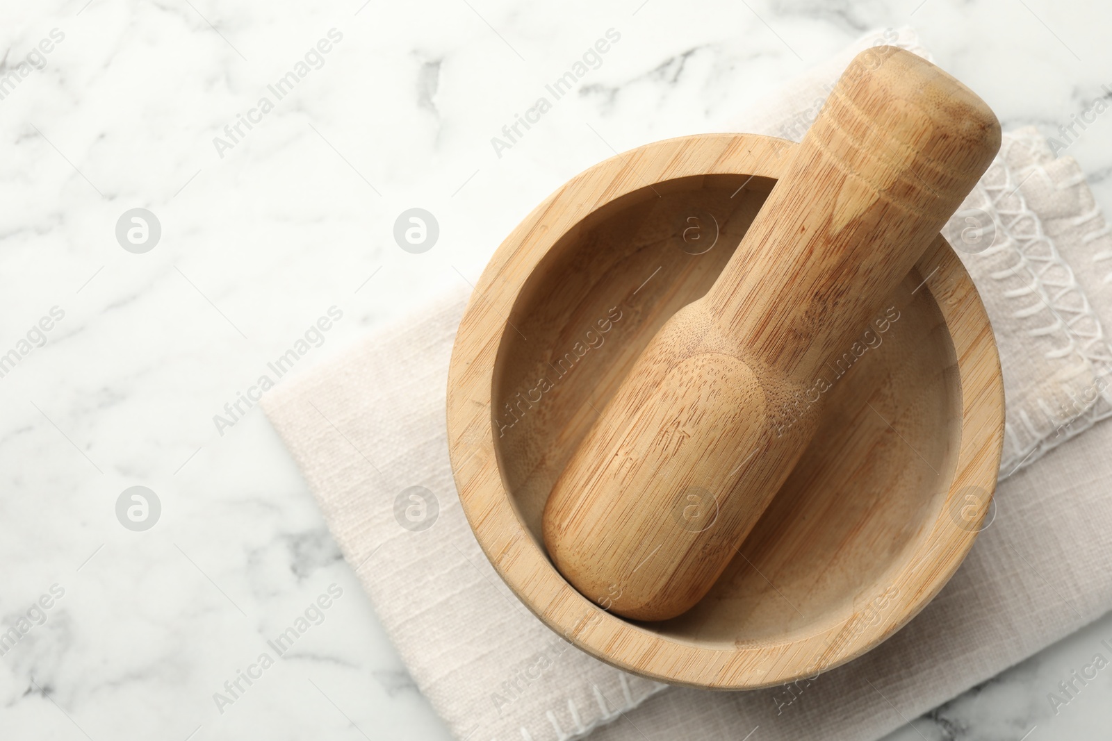 Wooden mortar, pestle and cloth on white marble table, top view. Space for text Photo of Wooden mortar, pestle and cloth on white marble table, top view. Space for text