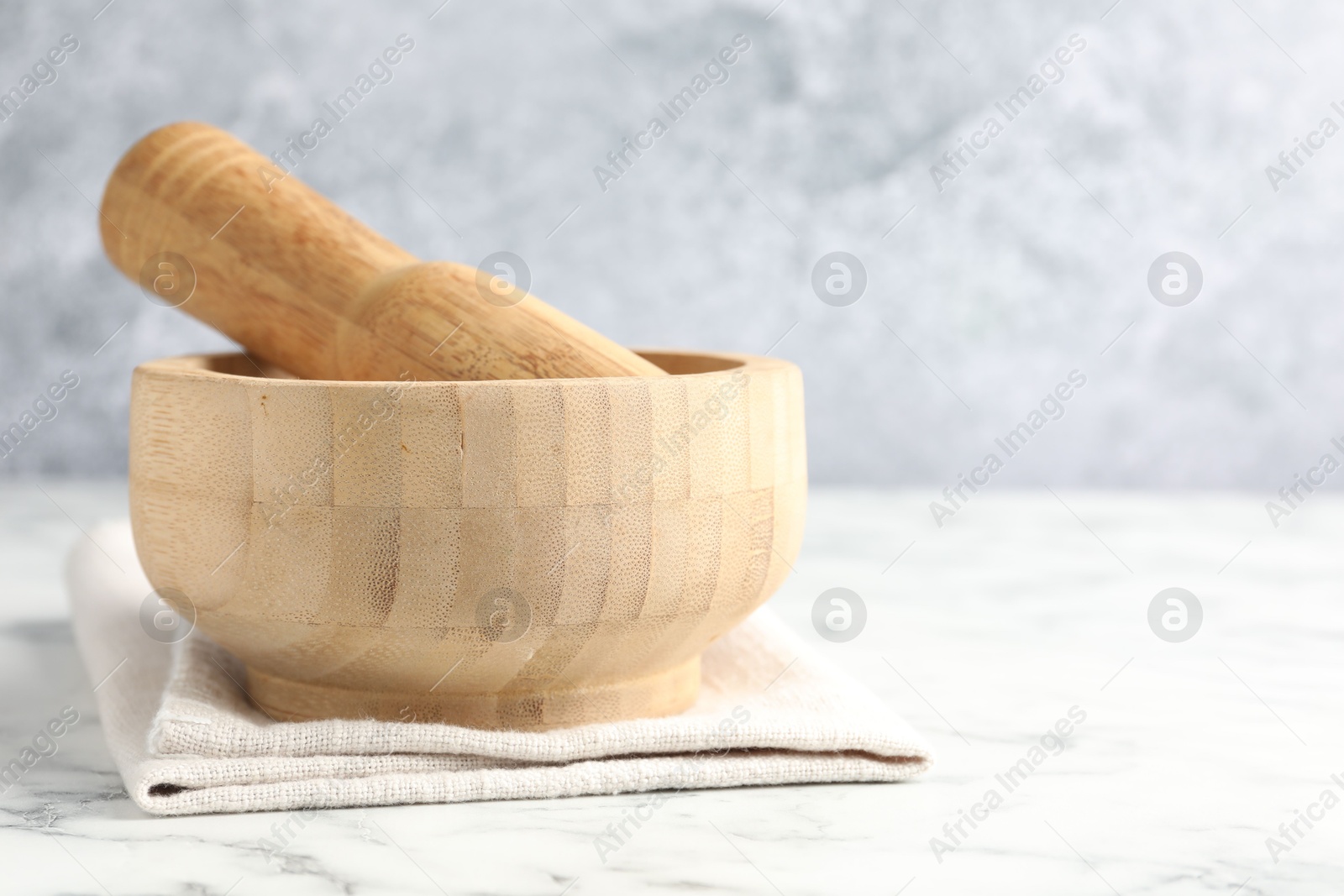 Wooden mortar, pestle and cloth on white marble table, closeup Photo of Wooden mortar, pestle and cloth on white marble table, closeup