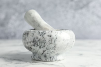 Photo of Mortar and pestle on white marble table, closeup