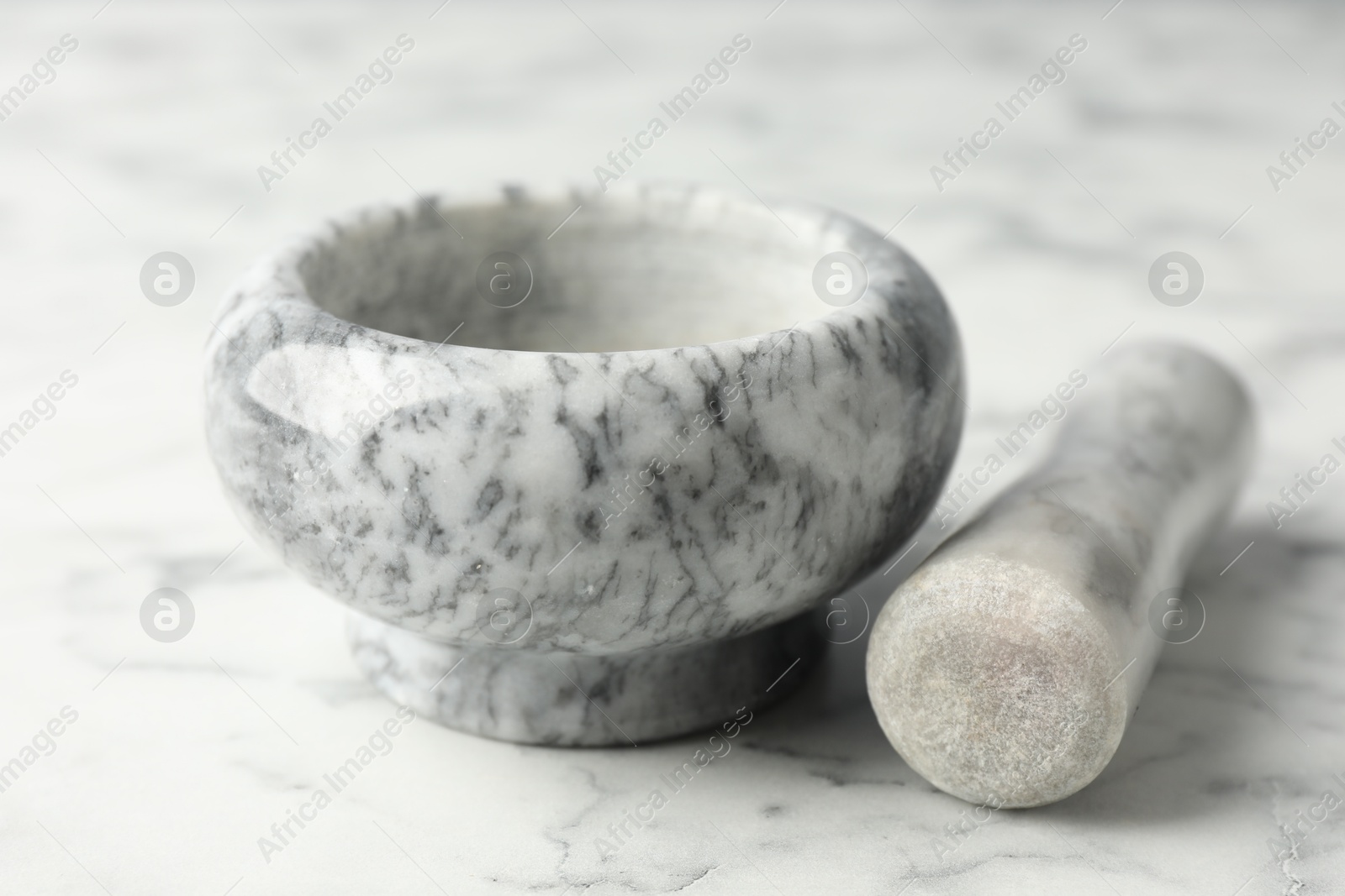 Mortar and pestle on white marble table, closeup Photo of Mortar and pestle on white marble table, closeup