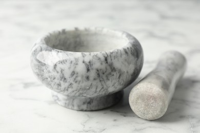 Photo of Mortar and pestle on white marble table, closeup