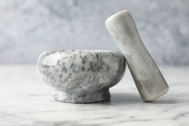 Photo of Mortar and pestle on white marble table, closeup