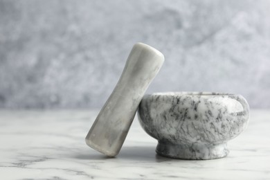 Photo of Mortar and pestle on white marble table, closeup