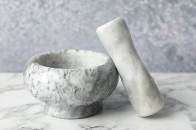 Photo of Mortar and pestle on white marble table, closeup