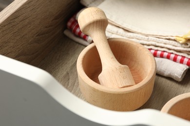 Photo of Wooden mortar and pestle in drawer indoors, closeup