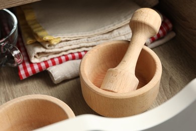 Photo of Wooden mortar and pestle in drawer indoors, closeup