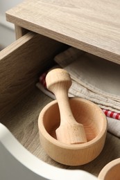 Photo of Wooden mortar and pestle in drawer indoors, closeup