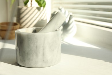 Photo of Marble mortar and pestle on windowsill indoors, closeup. Space for text
