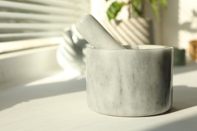 Photo of Marble mortar and pestle on windowsill indoors, closeup. Space for text