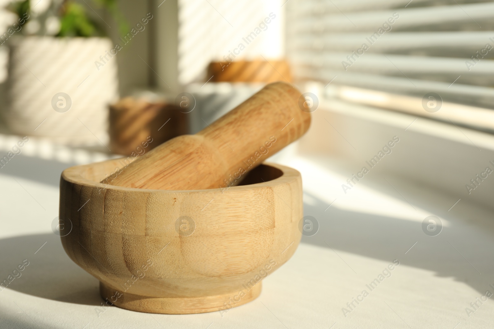 Wooden mortar and pestle on windowsill indoors, closeup. Space for text Photo of Wooden mortar and pestle on windowsill indoors, closeup. Space for text