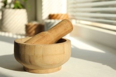 Photo of Wooden mortar and pestle on windowsill indoors, closeup. Space for text