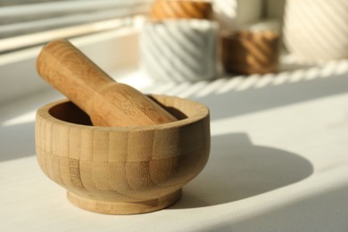 Photo of Wooden mortar and pestle on windowsill indoors, closeup. Space for text
